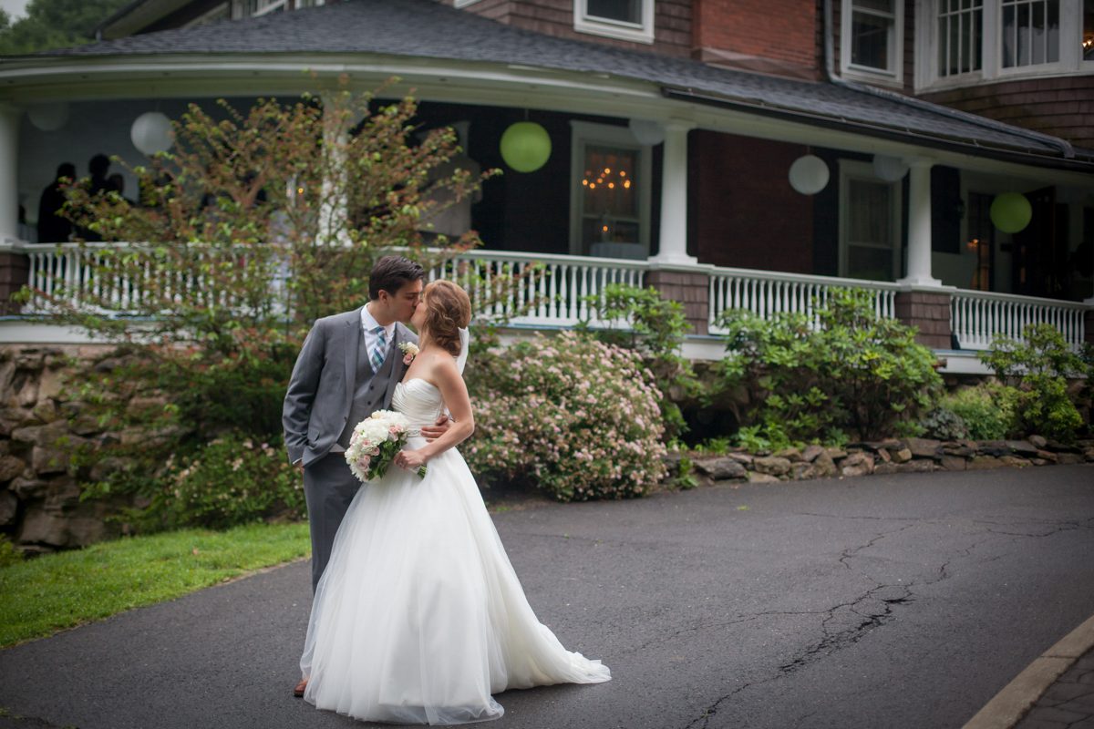Tent Weddings at Tarrywile Mansion bride and groom kissing in front of the decorated veranda