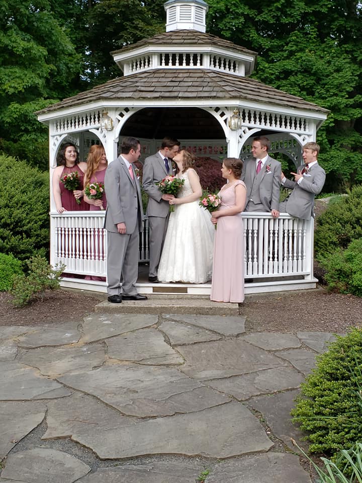 couple kissing in gazebo surrounded by wedding part